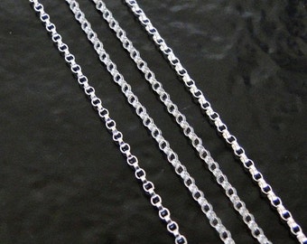 Puede incluir: Cuatro cadenas de plata de diferentes longitudes y grosores, dispuestas en paralelo sobre una superficie negra.