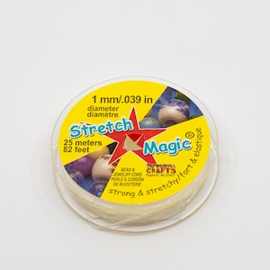 May include: A spool of clear elastic stretch magic bead and jewellery cord. The spool is yellow with black text that reads "Stretch Magic" and "1 mm/.039 in diameter". The spool also has the text "25 metres 82 feet" and "strong & stretchy/fort & elastique".