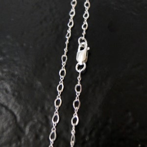 May include: A silver chain necklace with a lobster clasp closure. The chain is made of small, oval-shaped links.