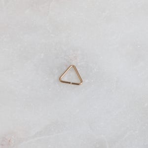 May include: A small gold triangle hoop earring.