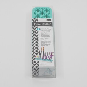 May include: A turquoise blue Keeper Crafter organizer with a grid of compartments for storing small craft supplies. The organizer is made of silicone and has a white label with the text "Keeper Crafter" and "1 piece/pièce/pieza".