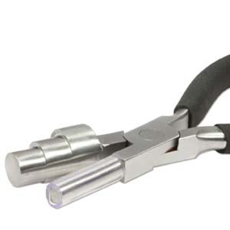 May include: Close-up of a silver metal jewelry making tool with a black handle. The tool has a cylindrical component on one side and a flat, rectangular component on the other. The tool is designed for shaping and manipulating metal.