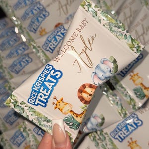 May include: A stack of white bags with green and blue jungle animal designs. The bags are labeled "Rice Krispies Treats" and "Welcome Baby Ayden".