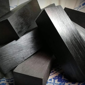 Peut inclure: Une pile de blocs en bois noir, chacun avec une surface lisse et polie. Les blocs sont dispos&eacute;s en quinconce, cr&eacute;ant une composition visuellement int&eacute;ressante.