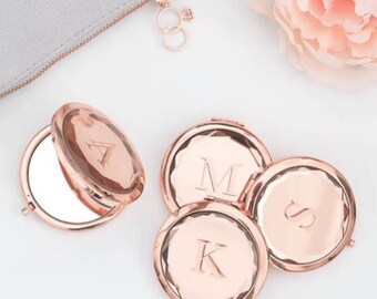 May include: Four rose gold compact mirrors with a laser engraved initial on each. The initials are A, M, K, and S.