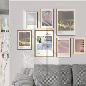 May include: A collection of framed art prints in various sizes and styles, displayed on a white wall above a gray sofa. The prints feature abstract designs and landscape photography, with a neutral color palette.