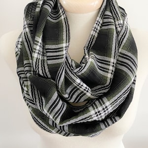 May include: A black, green and white plaid infinity scarf. The scarf is made from a soft, woven fabric and is ideal for adding a touch of style to any outfit.