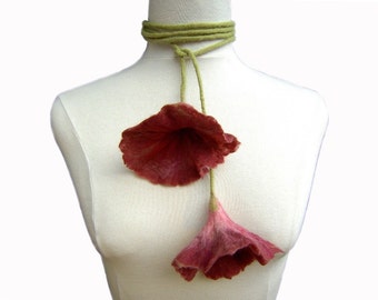 Puede incluir: Un collar de flores de fieltro con dos flores grandes de color rosa y un cordón de fieltro verde.