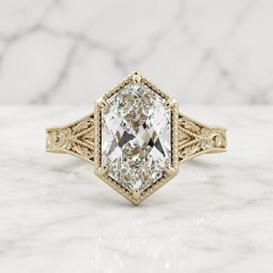 Elongated hexagon Duchess-cut lab grown diamond engagement ring in 14K yellow gold with milgrain bezel and filigree split shank.