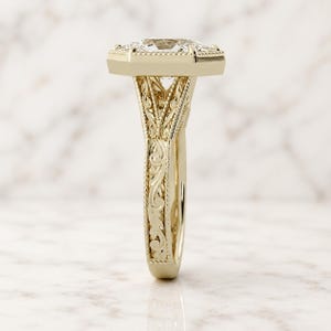 Side profile of a Duchess cut lab grown diamond engagement ring in 14K yellow gold with milgrain bezel, filigree scrollwork and split shank.