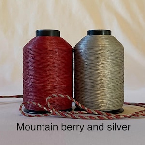 May include: Two spools of thread, one red and one silver. The red spool is labeled "Mountain Berry".