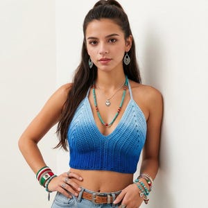 May include: A blue ombre crochet halter top with a V-neckline, featuring a gradient transition from light blue at the top to deep royal blue at the hem. The garment is sleeveless with a textured knit pattern and a cropped length.