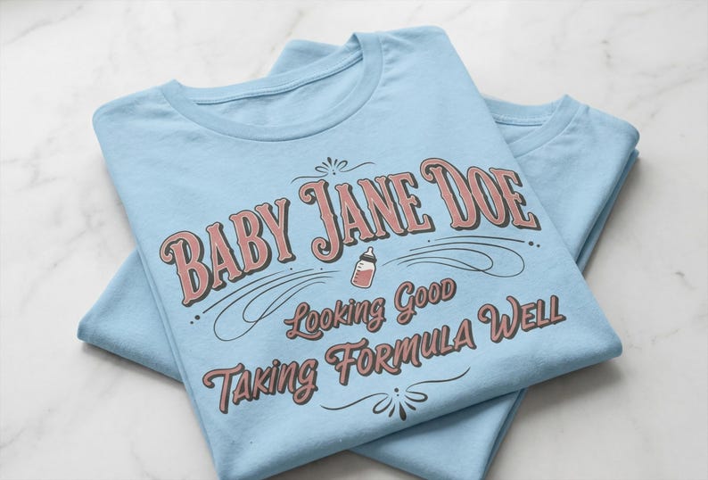 The pitt Baby Jane Doe funny slogan t shirt with baby bottle graphic, folded blue graphic tees stacked on marble background, clean product mockup image highlighting vintage typography humor design inspired by the pitt aesthetic and modern casual fashion trend