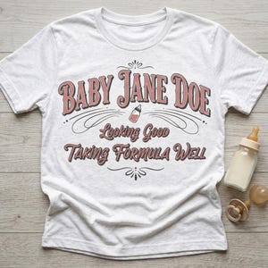 The Pitt Baby Jane Doe funny slogan t shirt with baby bottle graphic, white graphic tee flat lay with baby bottle and pacifier props on wooden background, styled product image highlighting vintage typography humor design inspired by the pitt aesthetic and modern casual fashion trend