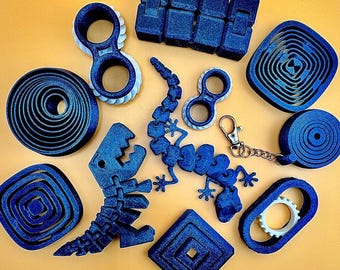 May include: A collection of blue fidget toys, including a segmented block, a dinosaur, a lizard, and several circular and geometric shapes. Some toys have white accents. A keychain is also included.