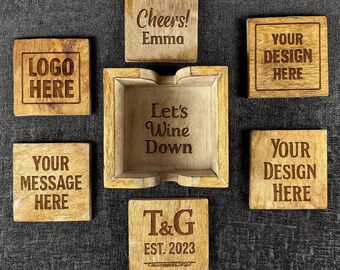 Może przedstawiać: Zestaw drewnianych podkładek i mała popielniczka. Podkładki mają wygrawerowany tekst, w tym "Cheers! Emma", "Your Message Here" i "Your Design Here". Popielniczka jest grawerowana z napisem "Let's Wine Down".