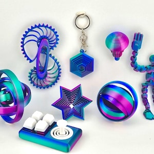 May include: A collection of colorful, iridescent 3D-printed objects. The items include a spiral, a keychain, a star, a sphere, a flexible figure, a joystick, and a geometric shape. The objects have a gradient of blue, purple, and green.