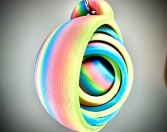 May include: A colorful, abstract pendant with a rainbow gradient of pink, yellow, green, and blue. The pendant is made of layered, curved shapes and is suspended from a silver chain.