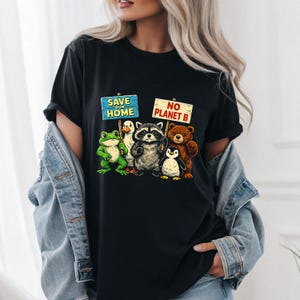 Könnte beinhalten: Schwarzes T-Shirt mit einer Grafik einer Frosches, einer Ente, eines Waschbären, eines Bären und eines Pinguins, die Schilder mit der Aufschrift "Save Our Home" und "No Planet B" halten. Das Design hat einen Vintage-Look.