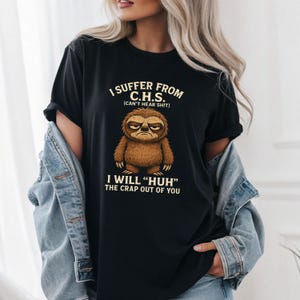 May include: Black t-shirt with the text "I SUFFER FROM C.H.S. (CAN'T HEAR SHIT) I WILL "HUH" THE CRAP OUT OF YOU" and a cartoon sloth illustration. The sloth is brown with an angry expression. The shirt is a casual wear item.
