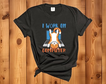 May include: Black t-shirt featuring a cartoon cat hanging upside down in front of a laptop. The text "I WORK ON COMPUTER" is above and below the cat and laptop illustration. The cat is orange and white.