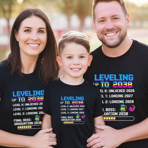 Puede incluir: Tres personas con camisetas negras con el texto "LEVELING UP TO 2038" en una fuente pixelada. Las camisetas también enumeran "LEVEL K: UNLOCKED 2026", "LEVEL 1: LOADING 2027" y "FINAL BOSS: GRADUATION 2038".