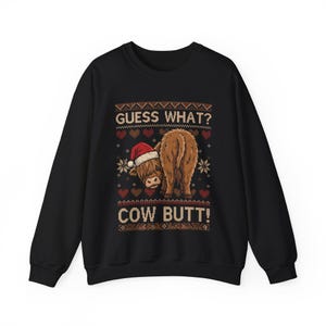 May include: Black sweatshirt with a humorous Christmas design. The graphic features a Highland cow wearing a Santa hat, with the text "GUESS WHAT? COW BUTT!" in a festive, sweater-like pattern. The design includes hearts and snowflakes.
