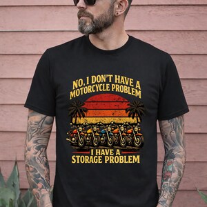 Puede incluir: Camiseta negra con un gráfico de motocicleta. El diseño presenta varias motocicletas en fila con un fondo de puesta de sol y el texto "NO, I DON'T HAVE A MOTORCYCLE PROBLEM I HAVE A STORAGE PROBLEM."