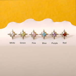 May include: Six star-shaped stud earrings with metallic points and square-cut center stones in white, green, pink, blue, purple, and red. Each earring is labeled below with its corresponding color name: White, Green, Pink, Blue, Purple, Red.