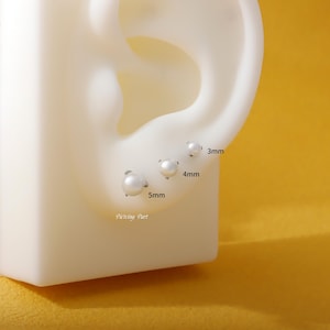 May include: A set of three pearl stud earrings, sized 3mm, 4mm, and 5mm, displayed on a white ear model. The earrings are round with a silver post. The text "Piercing Part" is visible.