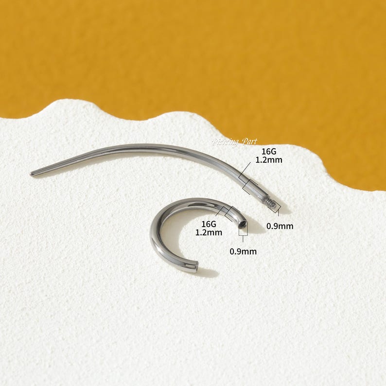 May include: A silver 16 gauge body piercing hoop with a 1.2 mm diameter. The hoop is open and has a 0.9 mm ball closure. The hoop is shown next to a straight barbell with a 1.2 mm diameter and a 0.9 mm ball closure.