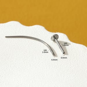 May include: Two silver 18 gauge body piercing bars, one straight and one curved. The straight bar is 1.0 mm long and the curved bar is 0.9 mm long. Both bars have a 0.9 mm ball end.