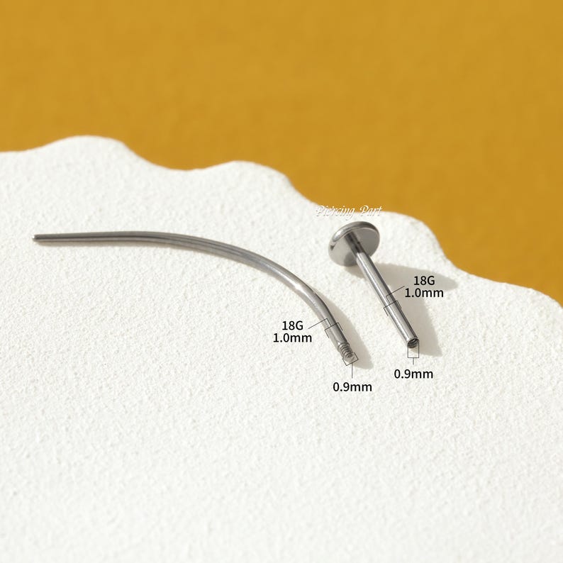 May include: Two silver 18 gauge body piercing bars, one straight and one curved. The straight bar is 1.0 mm long and the curved bar is 0.9 mm long. Both bars have a 0.9 mm ball end.