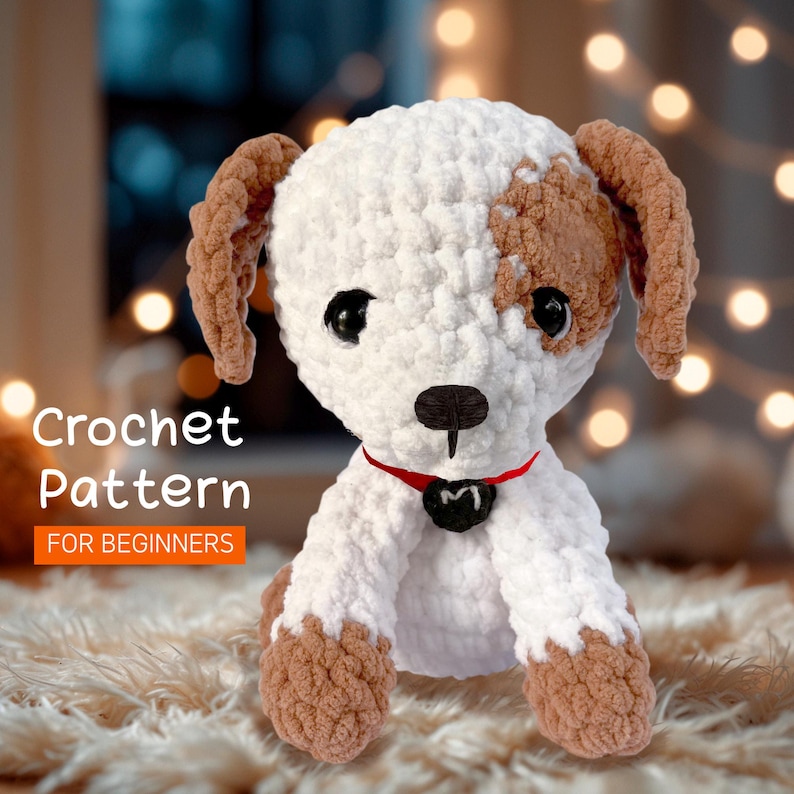 May include: Crocheted dog toy pattern for beginners. The dog is white with brown spots and a red collar with a black tag that says "M".