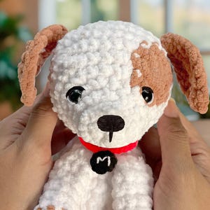 May include: A crocheted white and brown dog toy with a red collar and a black tag that says "M".