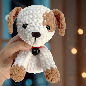May include: White and brown crocheted dog plush toy with a red collar and a black letter "M" on the collar.