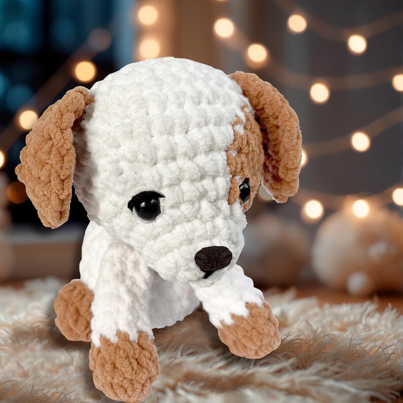 May include: A white and brown crocheted stuffed dog toy with black eyes and a black nose. The dog is sitting on a brown fuzzy surface.