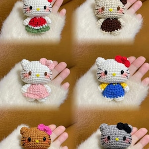 Peut inclure: Six poup&eacute;es Hello Kitty faites &agrave; la main au crochet. Chaque poup&eacute;e pr&eacute;sente un code couleur diff&eacute;rent, notamment blanc, marron, gris et beige, avec divers n&oelig;uds et tenues color&eacute;s. Les poup&eacute;es sont pr&eacute;sent&eacute;es sur une surface blanche et duveteuse.