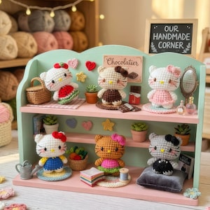 Peut inclure: Une &eacute;tag&egrave;re d'exposition avec plusieurs figurines Hello Kitty crochet&eacute;es, chacune avec des tenues et des accessoires uniques. L'&eacute;tag&egrave;re est peinte dans des couleurs pastel et comprend des plantes miniatures, un miroir et une enseigne indiquant "Our Handmade Corner."