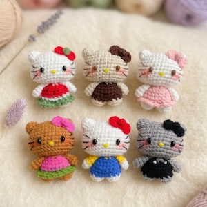 Peut inclure: Six poup&eacute;es au crochet faites &agrave; la main en forme de chat, chacune avec des tenues et des accessoires uniques. Les poup&eacute;es sont blanches, beiges, marron et grises, avec des robes et des n&oelig;uds color&eacute;s. Les poup&eacute;es sont dispos&eacute;es sur une surface cr&egrave;me.