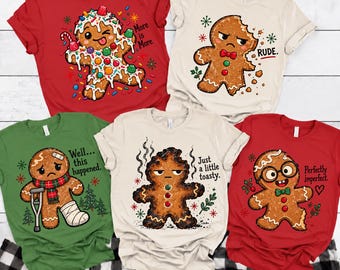May include: Five short-sleeve t-shirts in red, cream, and green featuring gingerbread character graphics. The designs include text: More is More, RUDE, Well... this happened, Just a little toasty, and Perfectly imperfect, with various holiday-themed accents.