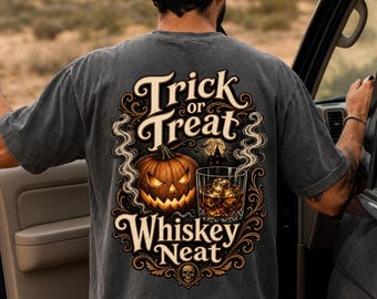 May include: A charcoal gray t-shirt featuring a back graphic with the text Trick or Treat Whiskey Neat. The design includes a glowing jack-o'-lantern, a glass of whiskey with ice cubes, swirling smoke, a haunted house silhouette, and a small skull.