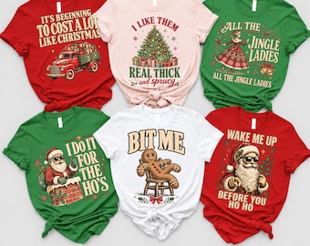 May include: Six short-sleeved t-shirts in red, light pink, green, and white. The shirts feature Christmas-themed graphics and text including It's Beginning To Cost A Lot Like Christmas, I Like Them Real Thick And Sprucy, All The Jingle Ladies, I Do It For The Ho's, Bit Me, and Wake Me Up Before You Ho Ho.