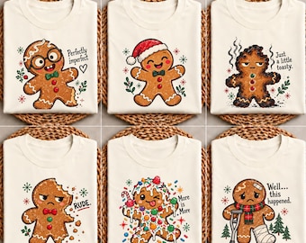 May include: Six cream-colored t-shirts featuring gingerbread character graphics. Designs include a gingerbread person with glasses, a Santa hat, a burnt cookie, a bitten cookie, a candy-covered cookie, and one with a crutch and bandage.