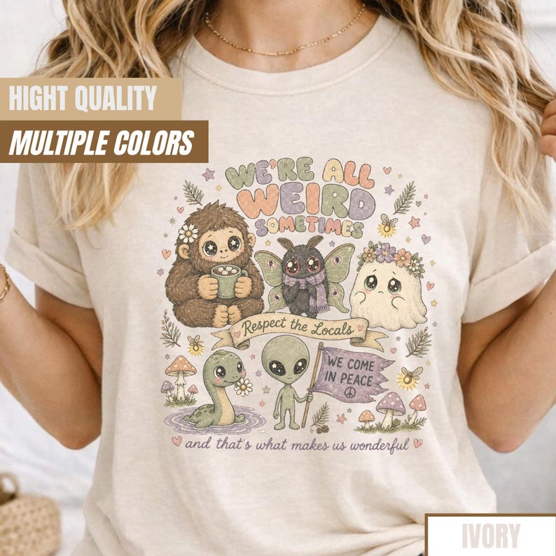 May include: Ivory-colored t-shirt featuring a whimsical illustration with the text "WE'RE ALL WEIRD SOMETIMES." The design includes a Bigfoot, a moth, a ghost, a dinosaur, and an alien. The phrase "Respect the Locals" is on a banner.