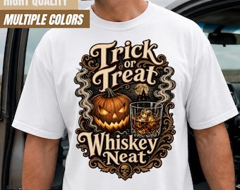 May include: A white t-shirt featuring a graphic print with the text Trick or Treat Whiskey Neat. The design includes a glowing jack-o'-lantern, a glass of whiskey with ice cubes, swirling smoke, and a dark silhouette of a haunted house.