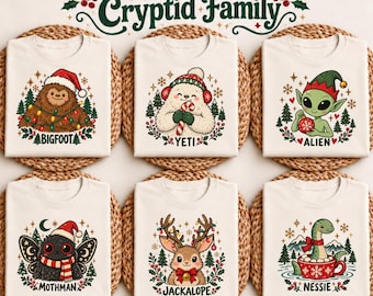 May include: Six off-white t-shirts featuring Christmas Cryptid Family text and illustrations of Bigfoot, Yeti, Alien, Mothman, Jackalope, and Nessie. Each shirt displays a festive creature with holiday elements like Santa hats, candy canes, ornaments, and lights.