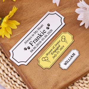 Puede incluir: Tres placas personalizadas para conmemoraciones y eventos. La más grande es blanca con texto negro: "Always in My Heart Frankie 04.06.2010~01.06.2020". Una placa amarilla dice "Bryson & Janice Engaged July 25, 2024". Una pequeña placa blanca dice "WILLIAM".