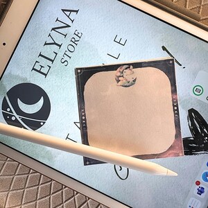 Peut inclure: Un iPad affiche le texte "ELYNA STORE" et un logo de croissant de lune. Un bloc-notes carré beige avec un motif céleste et un stylet blanc sont sur l'écran. Le bloc-notes a une bordure décorative et une petite illustration.