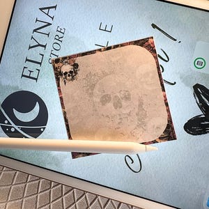 Peut inclure: Un bloc-notes carré avec un motif de crâne et une bordure florale. Le bloc-notes est posé sur un écran de tablette affichant "ELYNA STORE". Un stylet blanc est placé près du bloc-notes.